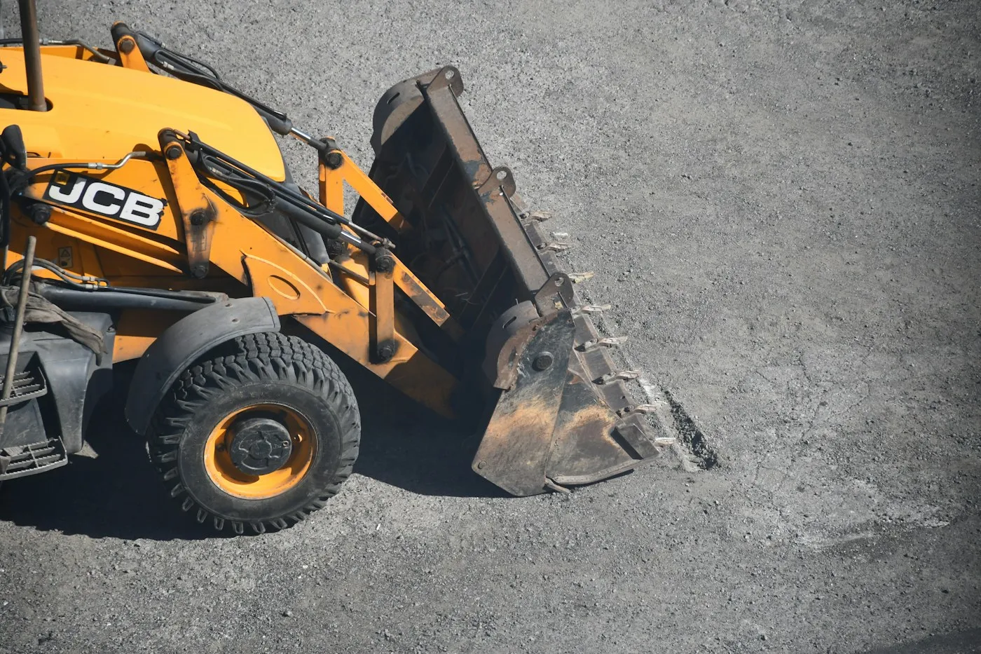 Retroescavadeira amarela movimentando materiais em uma área de obra